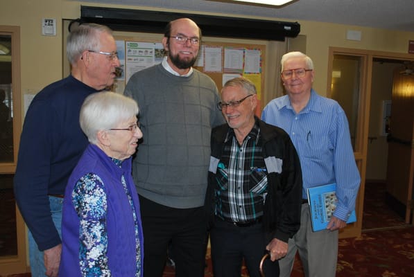Five residents and staff smiling in a common area