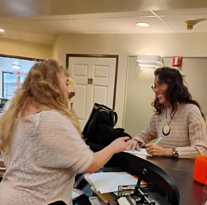 Staff member assisting a resident at the reception desk