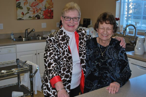 Staff member and resident smiling in a kitchen area