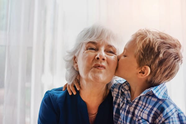 A child giving a kiss to a senior woman