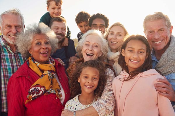 A diverse group of smiling seniors and family members outdoors