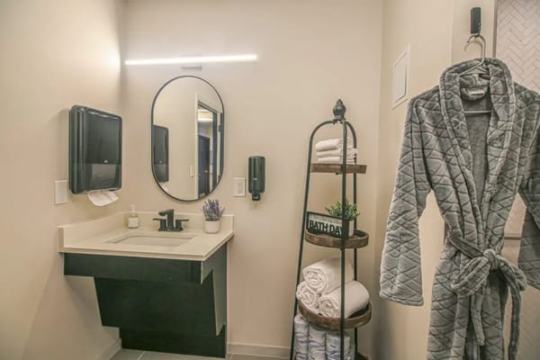 A well-lit and modern bathroom with a robe and towels