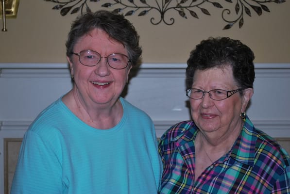 Two elderly women smiling together in a common area