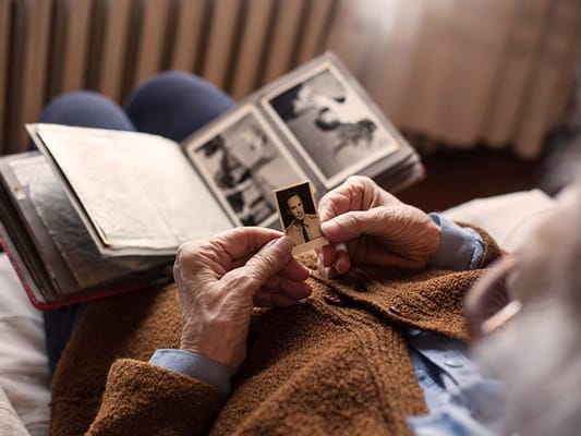 Elderly person holding a photograph from an album