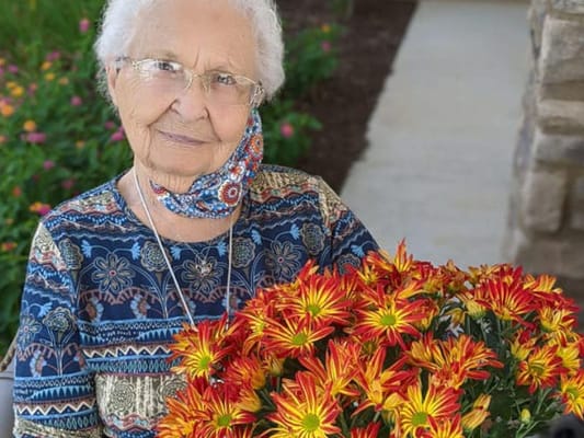 Senior resident holding a bouquet of flowers in a garden