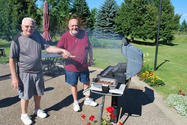 Two residents grilling outdoors in a landscaped area