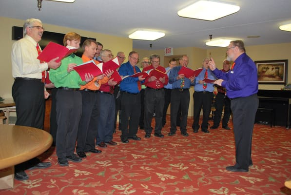 Group of men singing in colorful shirts during an event