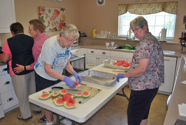 Residents preparing watermelon in a kitchen