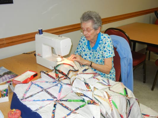 Resident sewing a quilt in an activity room