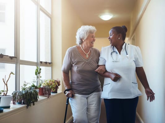 A caregiver assisting a senior resident in a hallway