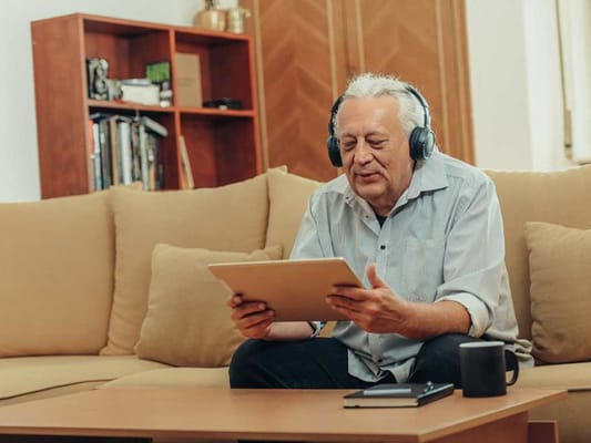 Senior man enjoying music with headphones in a cozy living room