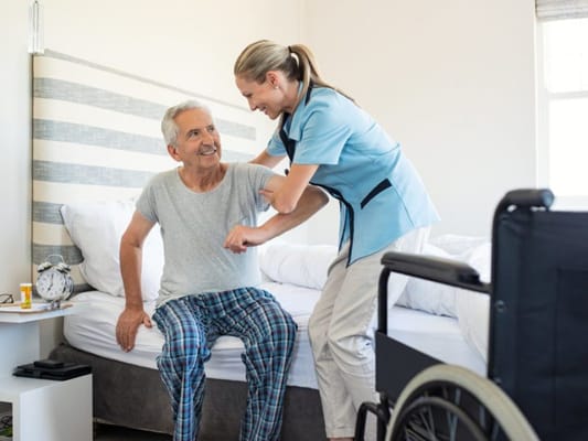 A caregiver assisting a senior man in a bedroom