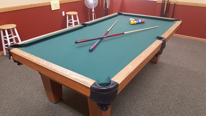 A billiards table with cues and balls set up