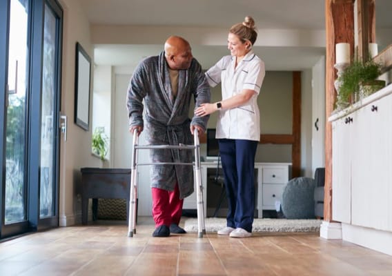 A caregiver assisting a resident in a facility's hallway