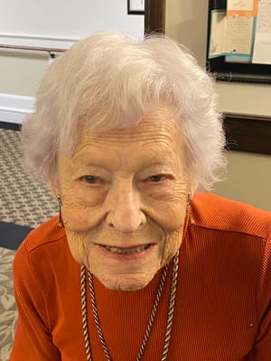 A smiling elderly woman in a bright interior