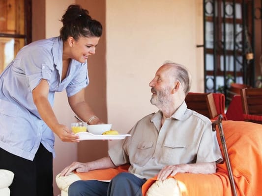 Caregiver serving food to a resident outdoors
