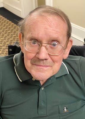 A smiling elderly man in a wheelchair