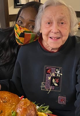 A staff member and resident smiling together with a turkey dinner