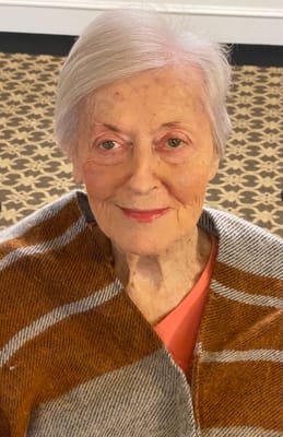 An elderly woman smiles warmly at the camera