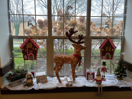 Decorative holiday display in a window with reindeer and decorations