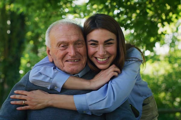 A smiling resident and staff member outdoors