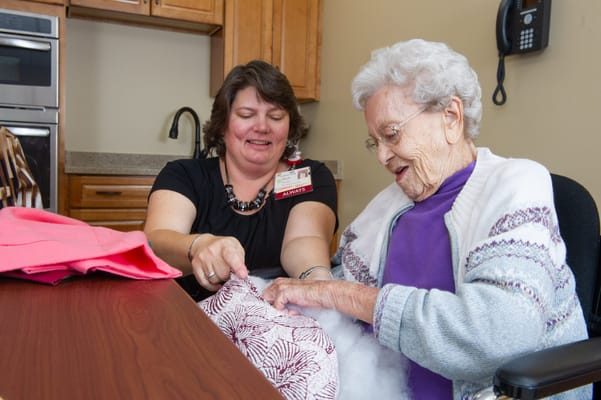 Staff member assisting a resident with a craft activity