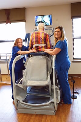 Therapist assisting a resident in rehabilitation equipment