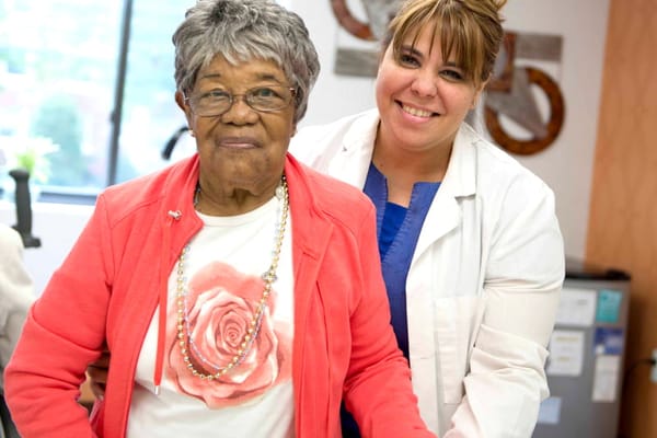 A resident and staff member smiling together in a facility