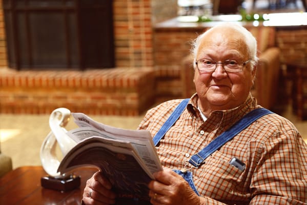 A senior gentleman reading a newspaper in a cozy common area