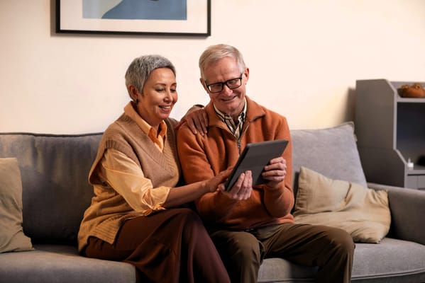 A senior couple enjoying a tablet together on a sofa