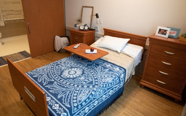 A comfortable bedroom featuring a bed with a blue patterned blanket and bedside table.