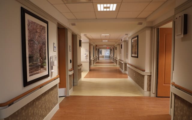 A clear hallway featuring artwork and doors in Albany County Nursing Home.