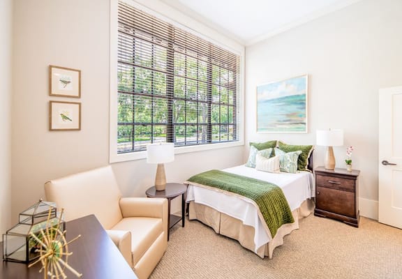 Bright private resident room with a bed and seating.