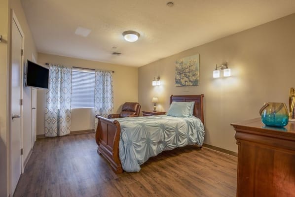 Bright bedroom with a blue bedspread and wooden furniture