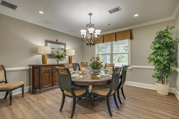A well-decorated dining room with a round table, elegant chairs, and a chandelier.