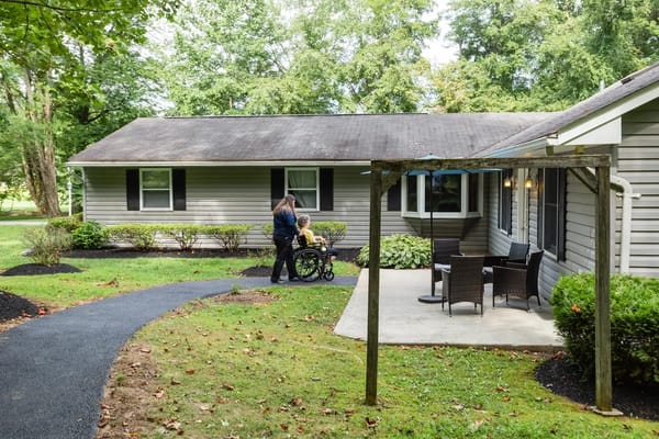 Staff assisting a resident in a wheelchair outside the building
