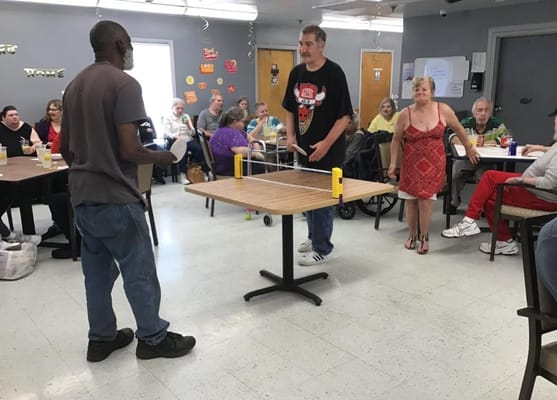 Residents engaged in a ping pong game in an activity room