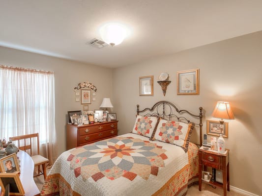 A beautifully decorated bedroom with a quilted bed and soft lighting