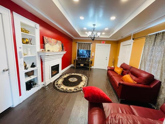 Cozy living room with red and yellow walls, two red sofas, and a decorative rug.