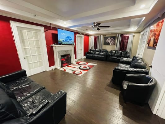 Comfortable black leather sofas in a living room with a red accent wall