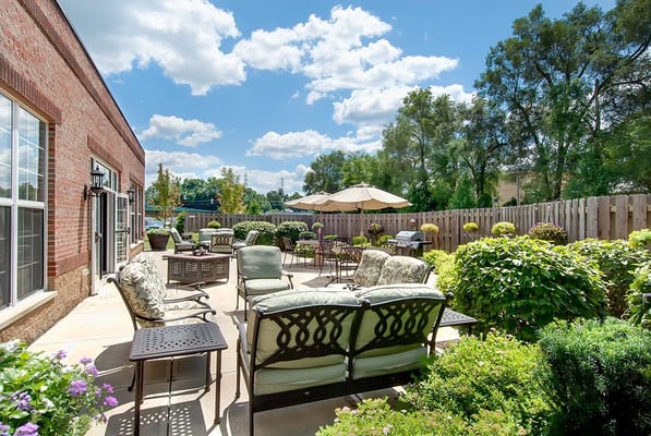 Outdoor seating area with chairs and tables surrounded by greenery
