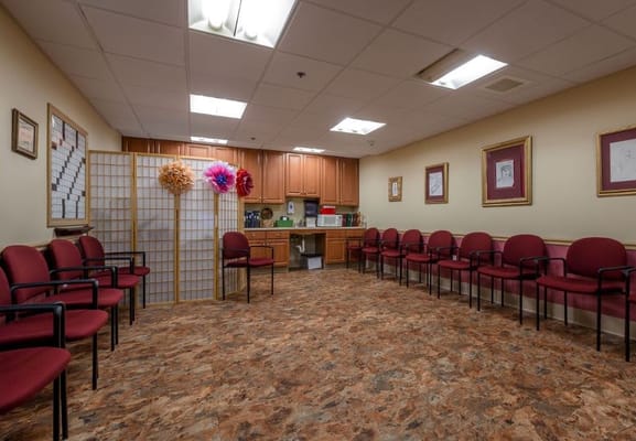 Activity room with red chairs and kitchen area