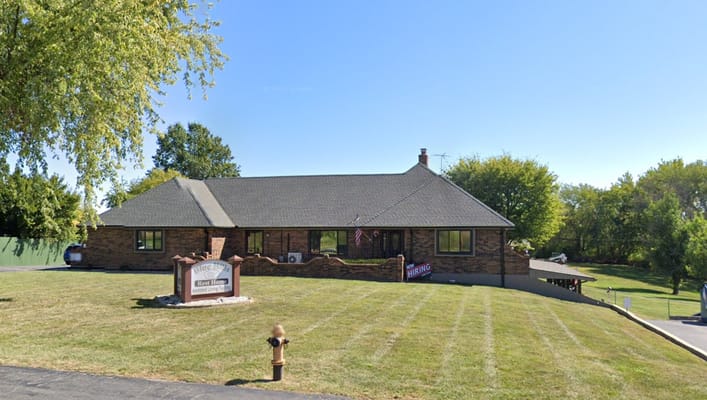 Exterior view of Blue Hills Rest Home with sign and lawn.
