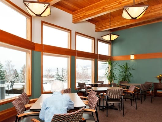 Senior resident sitting at a dining table in a bright lounge