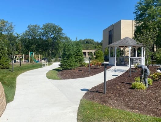 Pathway through landscaped outdoor area with gazebo and playground