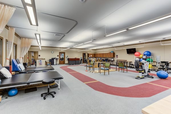 Spacious therapy room with exercise equipment and therapy tables.
