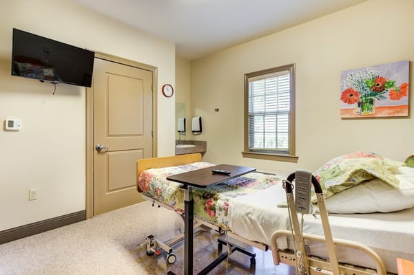 Interior view of a patient room with a bed, TV, and window