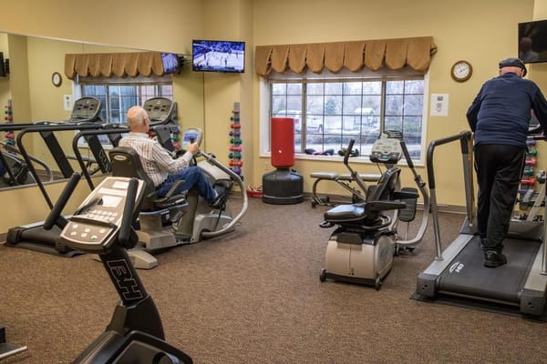 Residents exercising in a well-lit fitness center