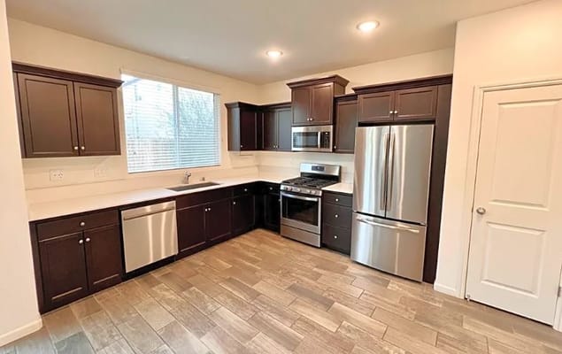 Shiny modern kitchen with dark cabinetry and stainless steel appliances.