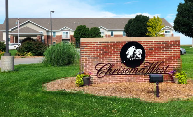 Signage for Chrisoma West with building in background